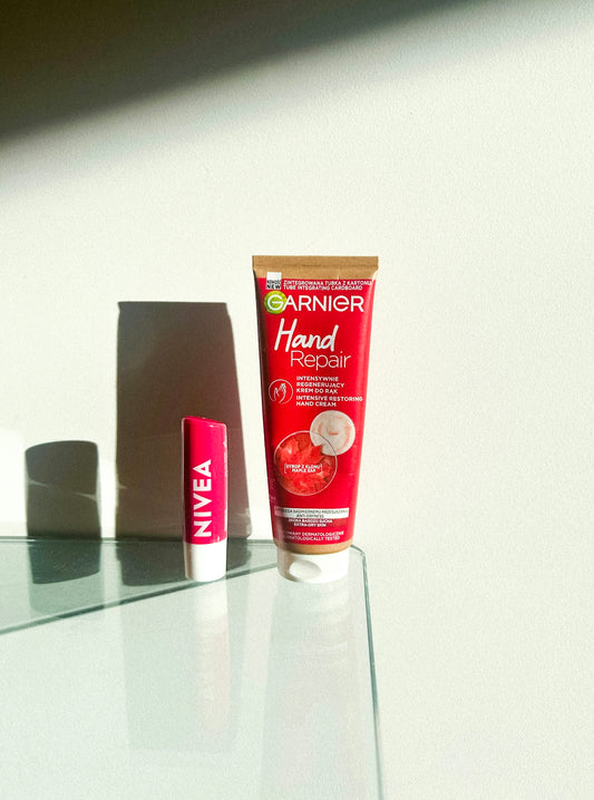 Garnier hand cream and nivea lip balm on glass table